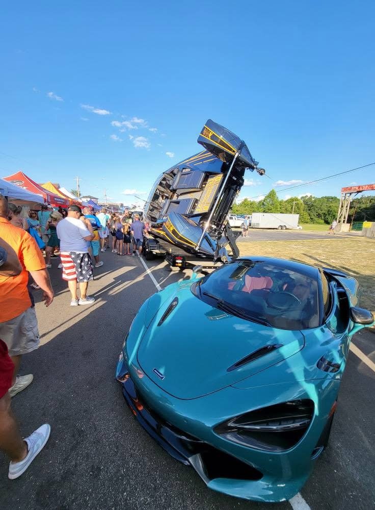 Platinum 428 tilted skyward on its trailer beside a McLaren at a boat show